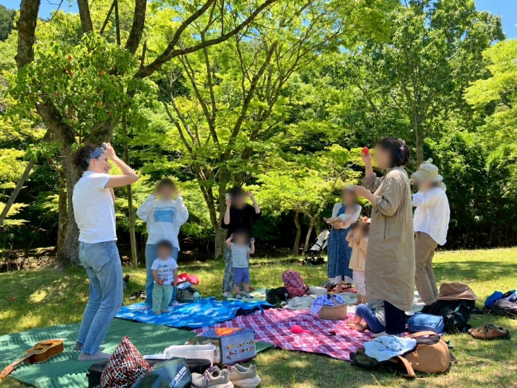 Jeweliann leading an outdoor music class for families under the trees at Takaragaike Park
